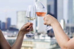 Zwei Personen stoßen an mit Blick auf Frankfurter Skyline