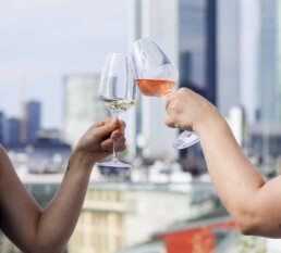 Zwei Personen stoßen an mit Blick auf Frankfurter Skyline
